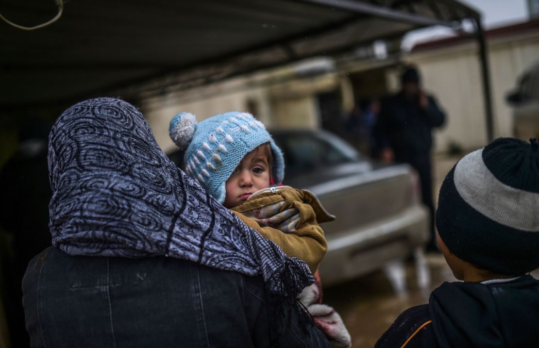 Refugees wait near the Turkish border crossing gate as Syrians fleeing the northern embattled city of Aleppo wait on February 6, 2016.