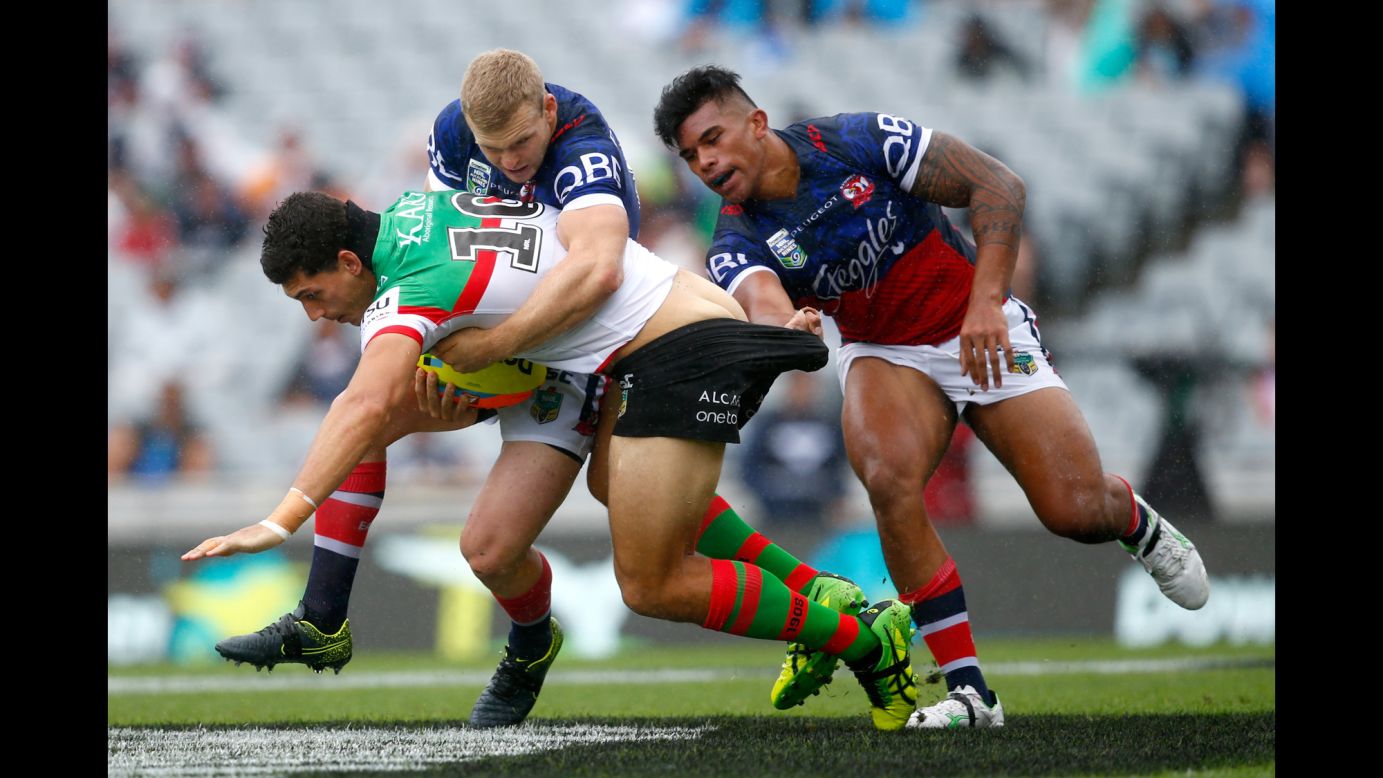 Kyle Turner, a rugby player with the South Sydney Rabbitohs, is tackled by two Sydney Roosters during an Auckland Nines match in Auckland, New Zealand, on Saturday, February 6.