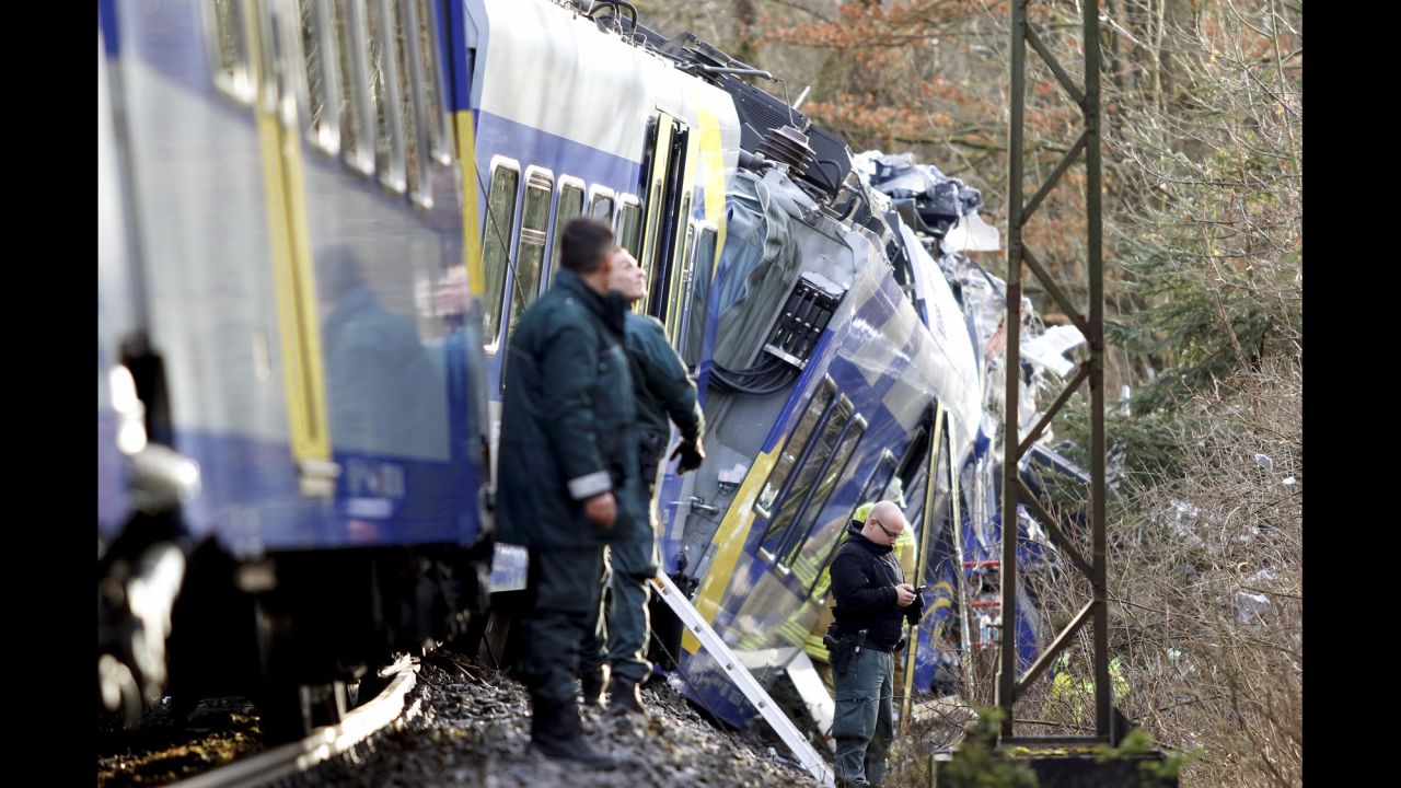 Police stand beside the trains as rescue personnel search the wreckage.