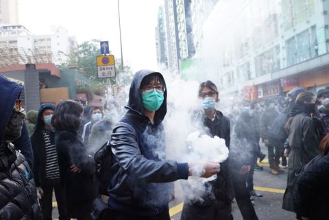 A protester holds a smoking object before throwing it at riot police on February 9.