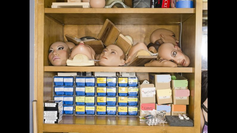 RealDoll faces, both male and female, sit on a shelf.