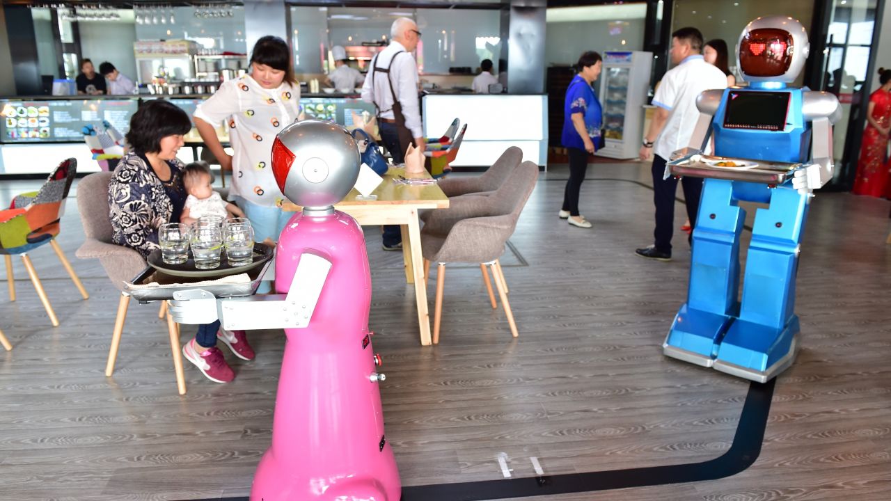 YIWU, CHINA - MAY 18:  (CHINA OUT) A couple of robot waiters deliver meals for customers at robot-themed restaurant on May 18, 2015 in Yiwu, Zhejiang province of China. Sophomore Xu Jinjin in 22 years old from Hospitality Management of Yiwu Industrial and Commercial College managed a restaurant where a pair of robot acted as waiters. The "male" one was named "Little Blue" (for in blue color) and the "female" one was "Little Peach" (for in pink) and they could help order meals and then delivered them to customers along the magnetic track and said: "Here're your meals, please enjoy". According to Xu Jinjin, They had contacted with the designer to present more robot waiters to make the restaurant a real one that depends completely on robots.  (Photo by ChinaFotoPress via Getty Images)