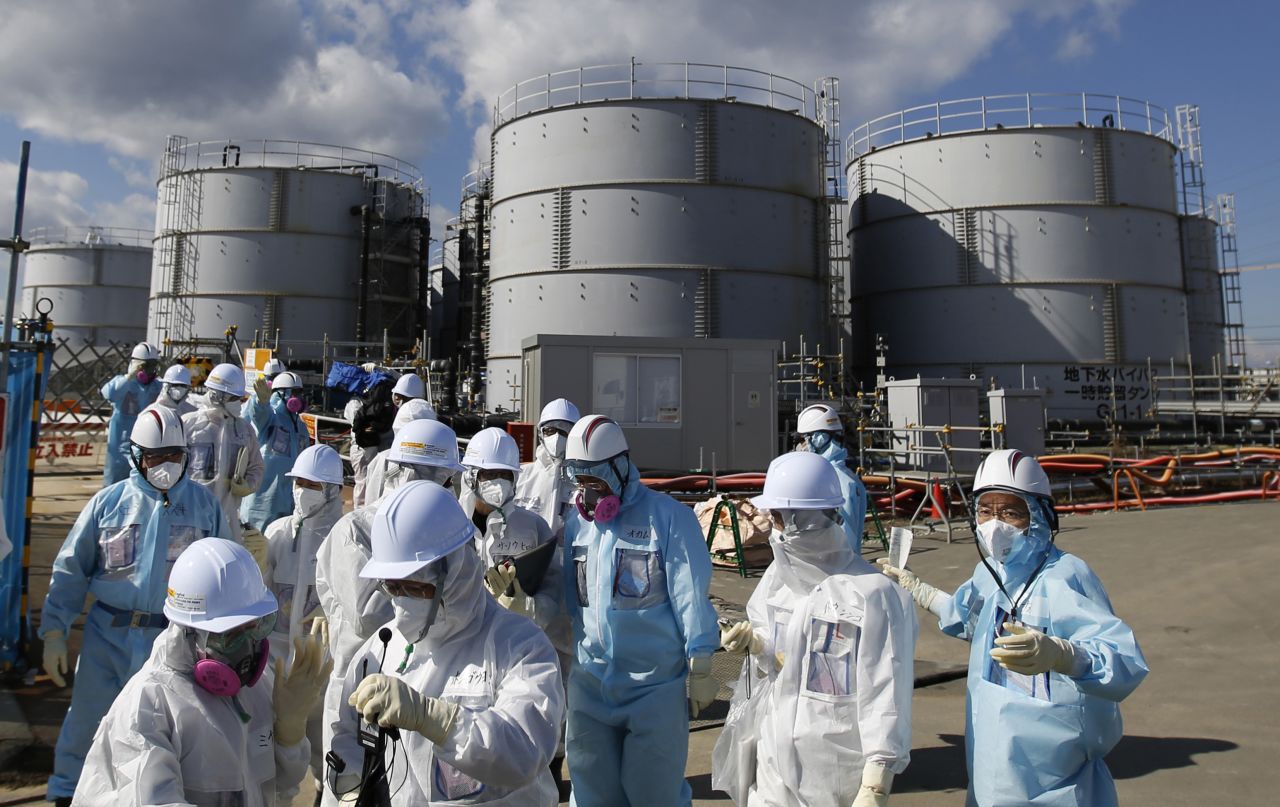 TEPCO employees, in blue protective suits, brief a press group in front of storage tanks for radioactive water on Februray 10.
