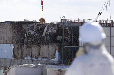 A member of the tour group, donning a protective suit and a mask, takes a look at the crippled No. 3 reactor on February 10.