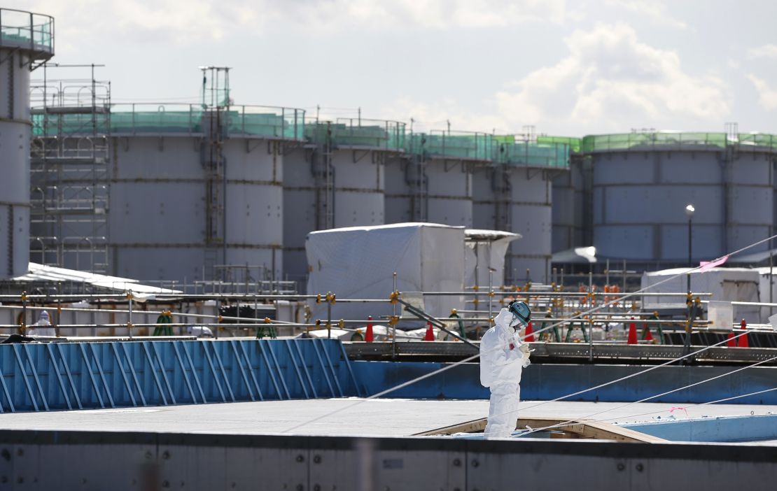 A worker takes notes in front of storage tanks for radioactive water at the Fukushima Daiichi nuclear plant on February 10.