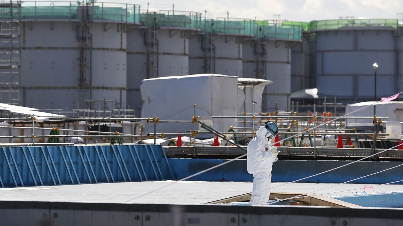 A worker takes notes in front of storage tanks for radioactive water at the Fukushima Daiichi nuclear plant on February 10.