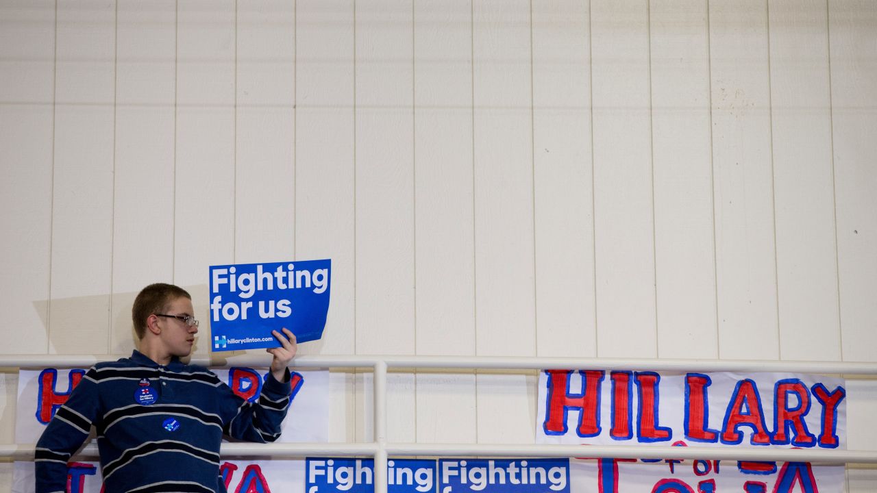 Hillary Clinton has used the slogan, "Hillary for America" and also had supporters display posters saying "Fighting for us." A member of the audience holds a campaign sign at the top of a set of bleachers as Clinton speaks in Iowa on January 30.