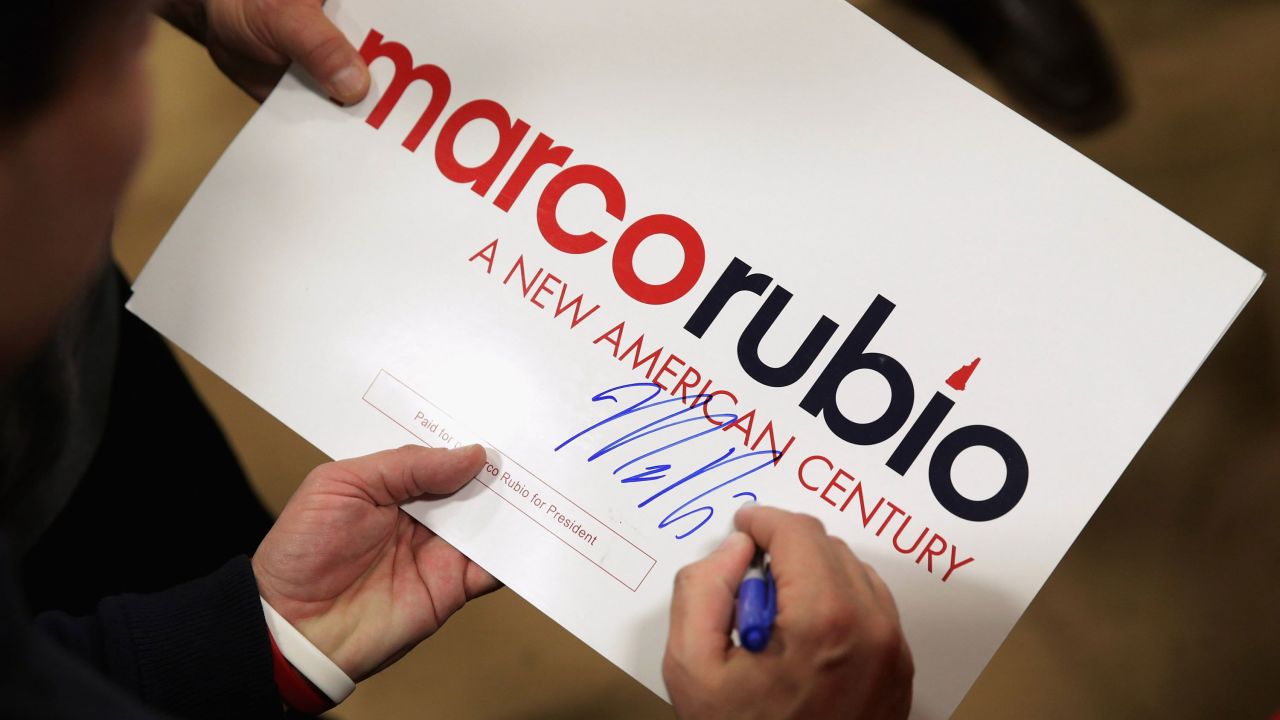 Republican presidential candidate Sen. Marco Rubio signs autographs under his "A New American Century" slogan at a campaign rally February 5.