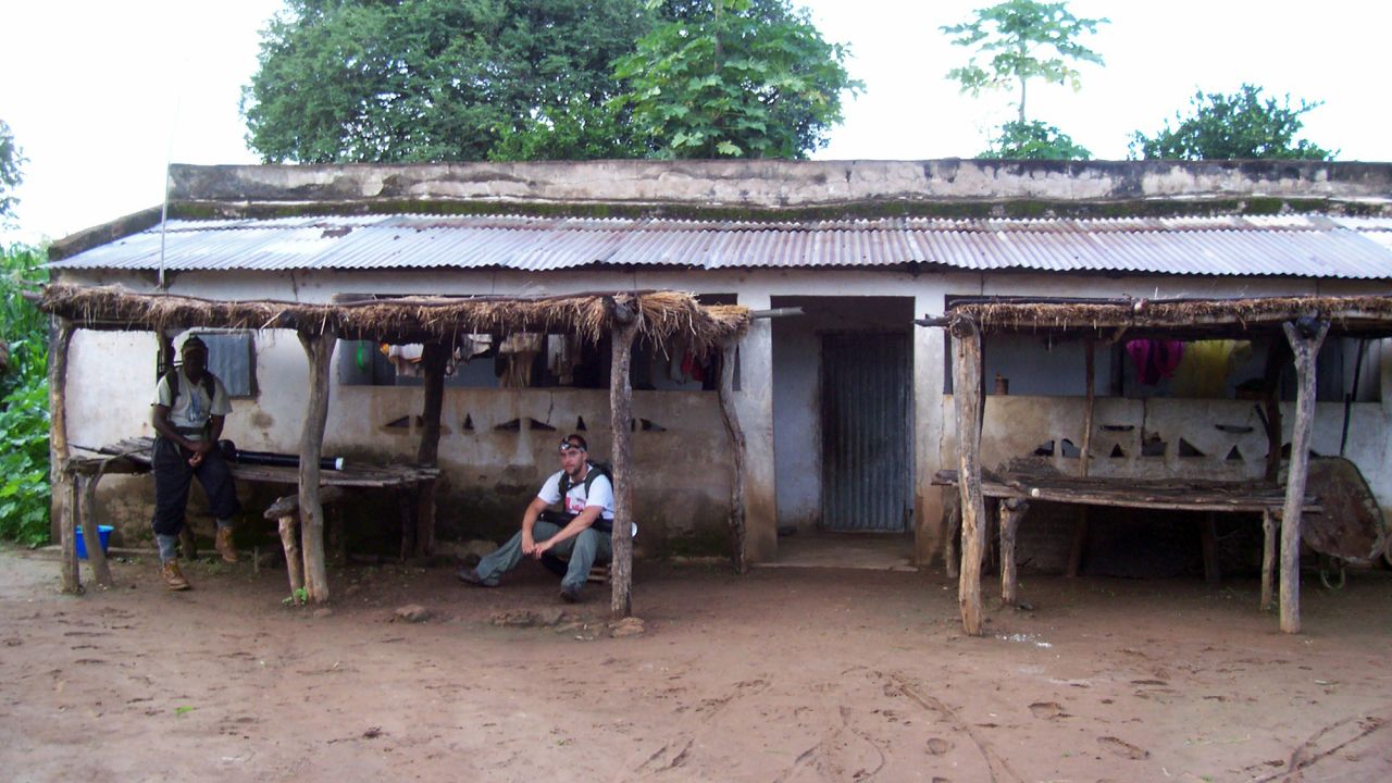 African researcher Massamba Sylla, left, and graduate student Kevin Kobylinski visit a villager's home in Ibel, Senegal. 