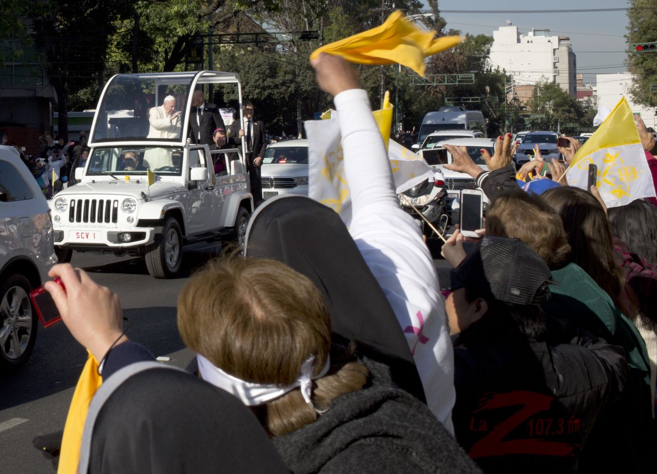 People wave to Pope Francis as he makes his way to Mexico City's main square. 