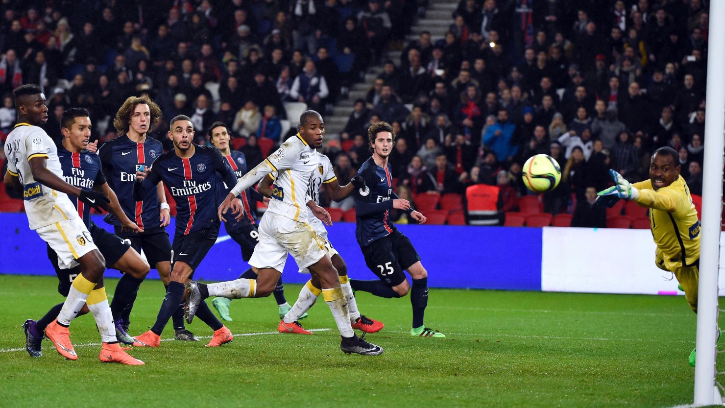 Lille's Nigerian goalkeeper Vincent Enyeama (R) dives for the ball as PSG players look on.