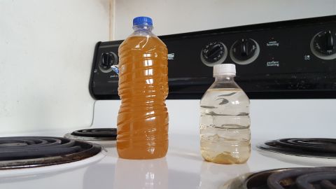 Garrett Boyte saves bottles of tap water collected from his faucet. The one on the right shows sediment at the bottom; the bottle on the left was recently shaken. 