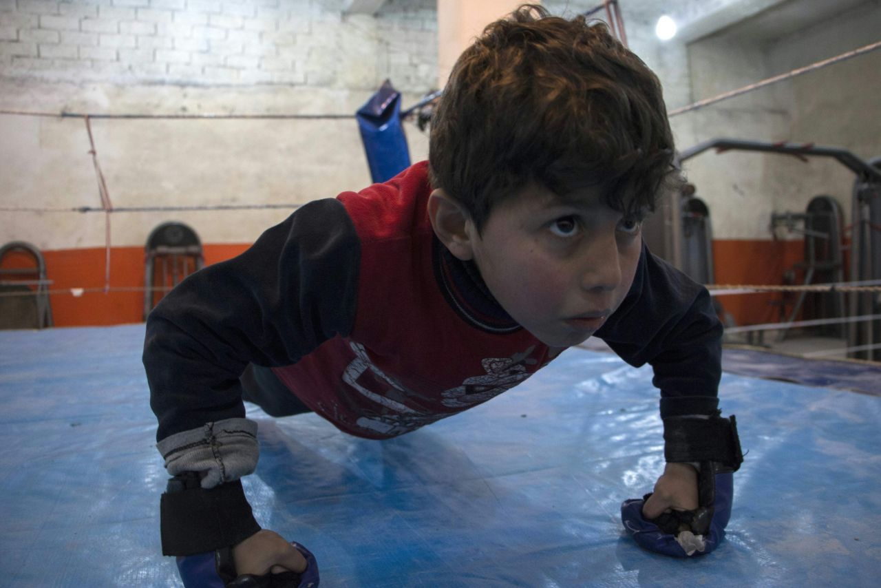 A young Syrian boy practices push-ups during a training session at the Shahba boxing club in Aleppo on February 10, 2016.