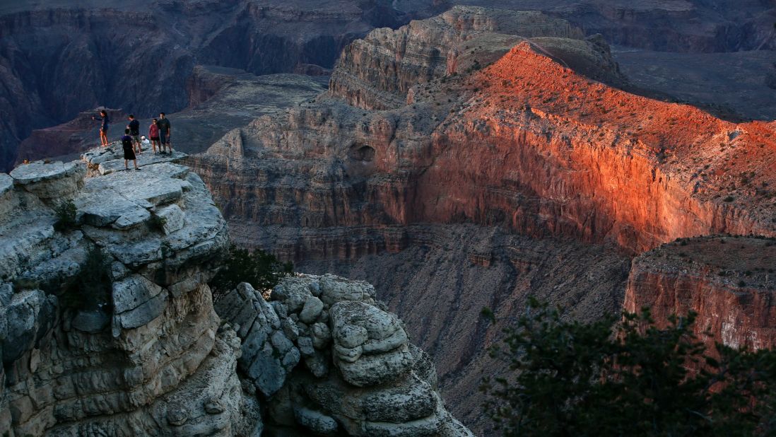 Second place <a href="http://www.cnn.com/2013/07/25/travel/grand-canyon-summer-park/">Grand Canyon National Park</a> in Arizona welcomed more than 5 million visits last year, a record for the park. As the National Park Service marks its centennial birthday year, officials are expecting more visitors at many of the nation's park sites. Visitors are shown here at sunset on the Southern Rim of Grand Canyon National Park standing on a cliff off of the Rim Trail.