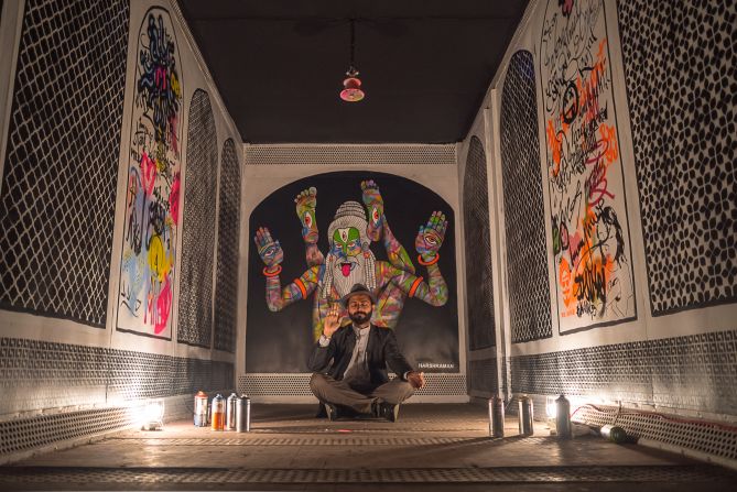 Artist Harsh Raman sitting inside his painting shipping container, again in his signature colorful style. <em>(Photograph by Naman Saraiya)</em>