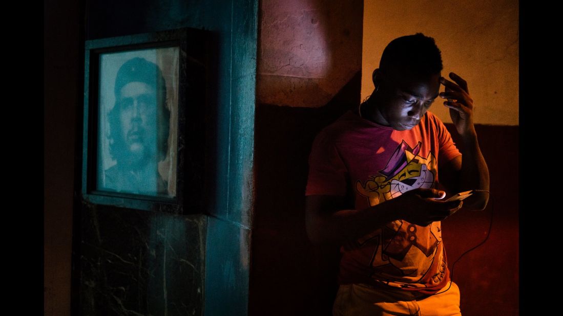 A boy in Havana, Cuba, explores the Internet on his phone near a photo of Che Guevara. In June, the country's government installed Wi-Fi hotspots in major cities.