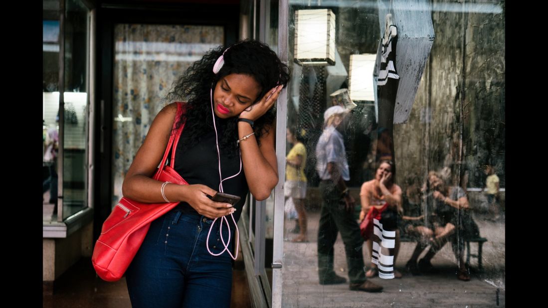 A young woman in Havana chats with a friend using Wi-Fi.