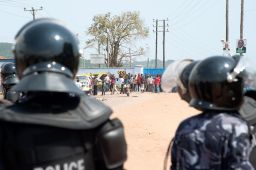Riot police watch opposition supporters in a suburb of Kampala, Uganda, on February 18, 2016. 