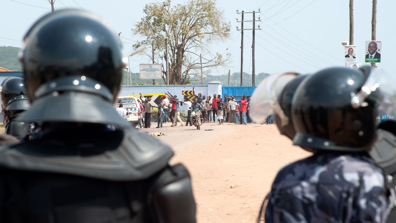 Riot police watch opposition supporters in a suburb of Kampala, Uganda, on February 18, 2016. 