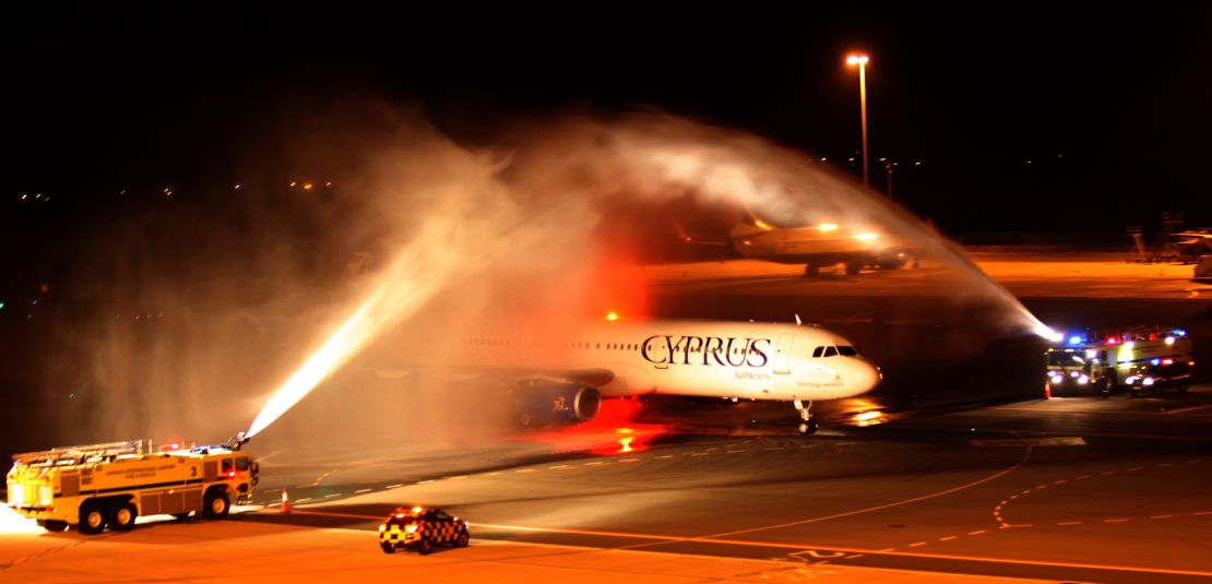 The plane carrying Pavlos Kontides taxies under a victory water arch laid on by the fire service after landing at Larnaca Airport.