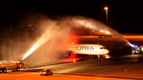 The plane carrying Pavlos Kontides taxies under a victory water arch laid on by the fire service after landing at Larnaca Airport.