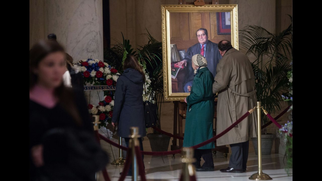 People look at a portrait of Scalia while paying their respects in Washington on February 19.