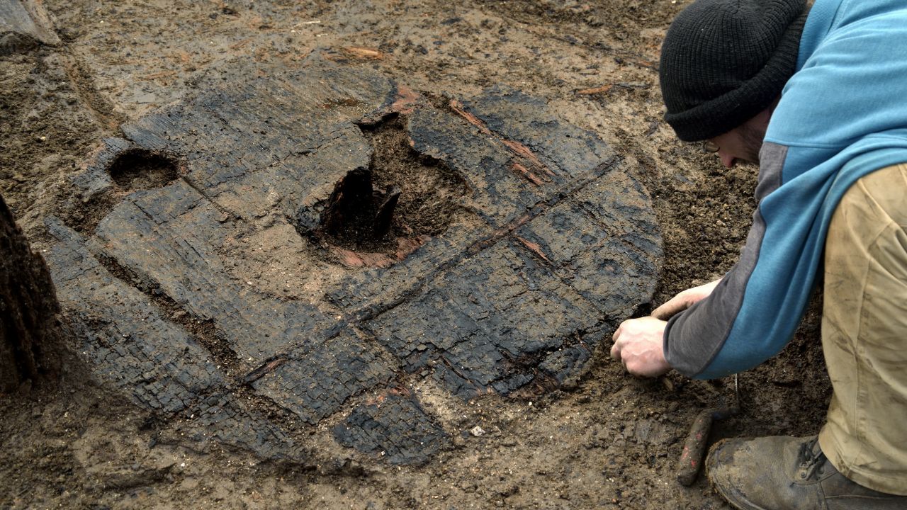 Archaeologists carefully uncover the 3,000-year-old wheel at England's Must Farm excavation site.