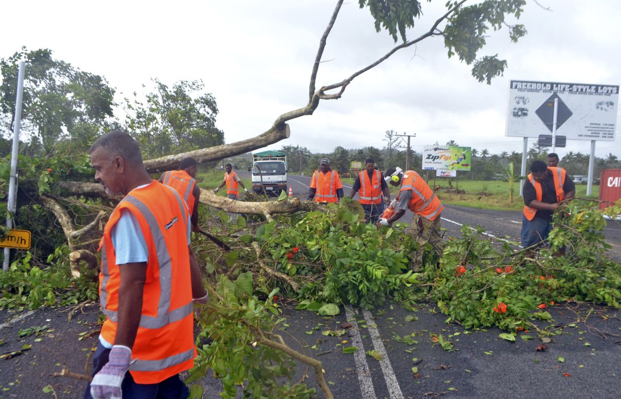 Road workers remove a fallen tree blocking a road near Lami, Fiji, on Sunday, February 21, after Cyclone Winston ripped through the country.