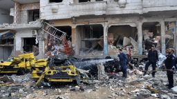 Syrian firefighters spray water on burning car on Sunday, February 21 at the site of a double car bomb attack in the al-Zahraa neighborhood of the Syrian city of Homs.