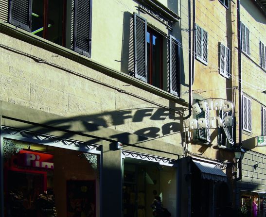 Afternoon sun casting shadows from the Caffè Astra sign in Pisa.