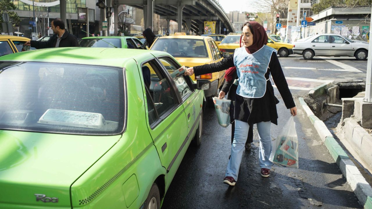 A woman slips campaign material into a car in Tehran.