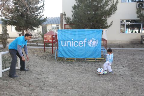 Murtaza dribbles as a UNICEF staffer takes on the role of goalkeeper.