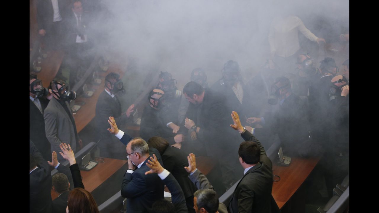 Lawmakers of Kosovo's ruling parties vote in the foreground as opposition lawmakers throw tear gas during a parliamentary session in Pristina, Kosovo, on Friday, February 19. The opposition was protesting agreements the government had made with Serbia.
