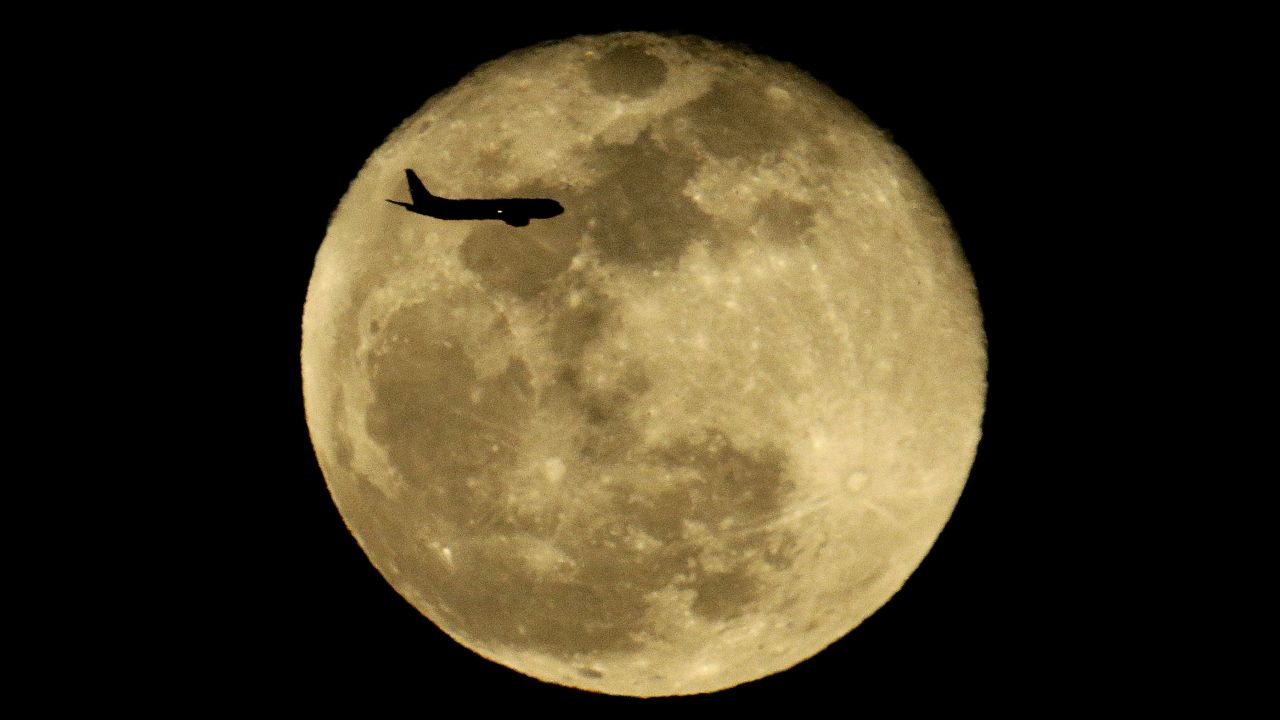 A passenger jet passes in front of a full moon as it approaches Phoenix's airport on Tuesday, February 23.