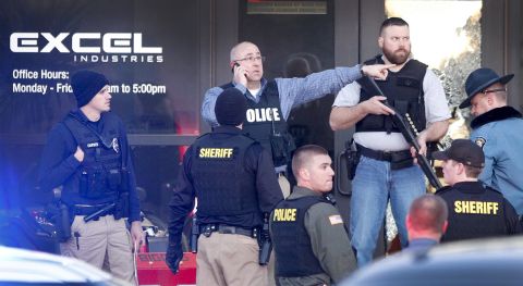 Several officers stand at the front door of Excel Industries in Hesston, Kansas, where a series of shootings that left multiple dead ended on Thursday, February 25. The suspected shooter, an employee at Excel, was killed by authorities.