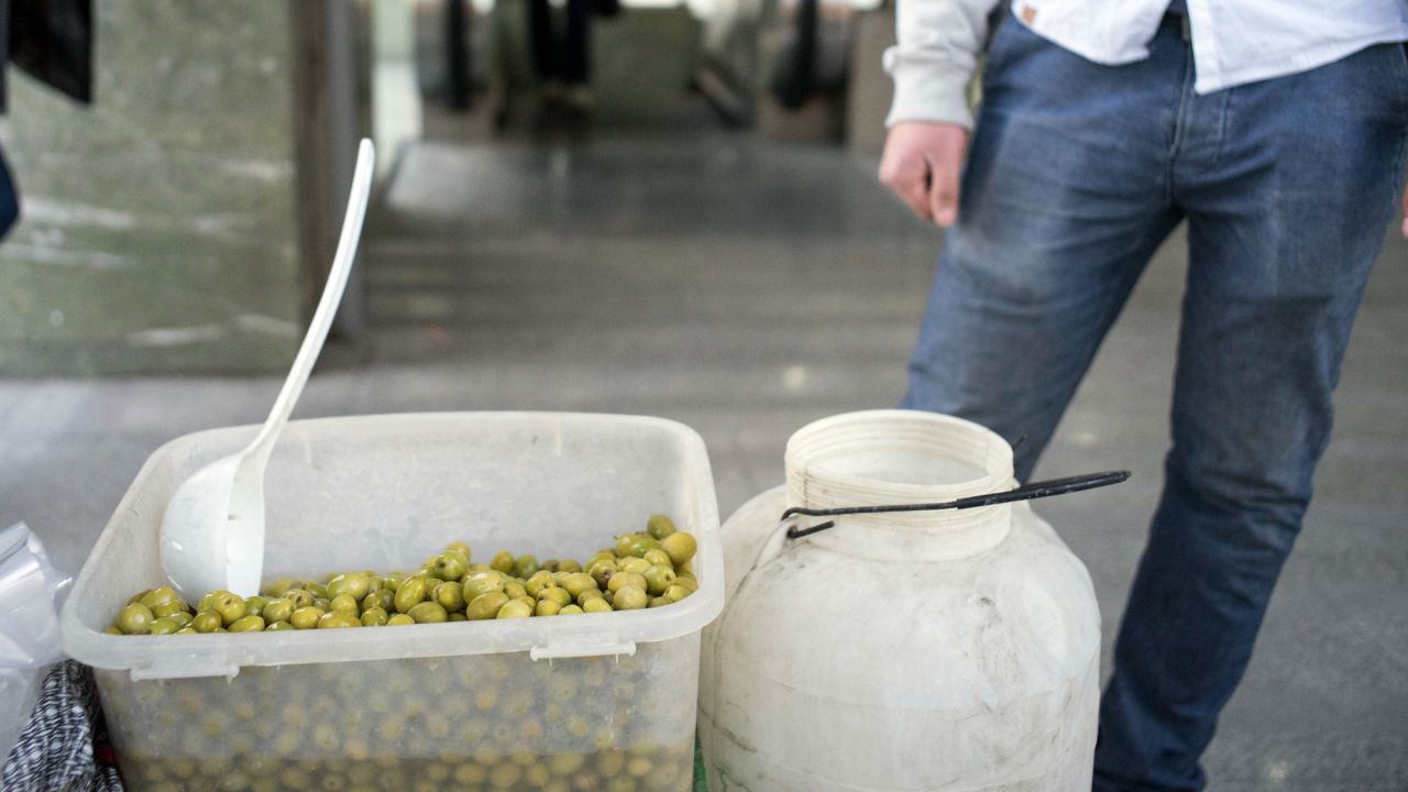 A man sells olives for hungry commuters outside one station.