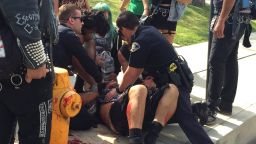 Police officer help a man injured when Ku Klux Klan demonstrators and counter-protesters fought in Anaheim, California, on Saturday, February 27.
