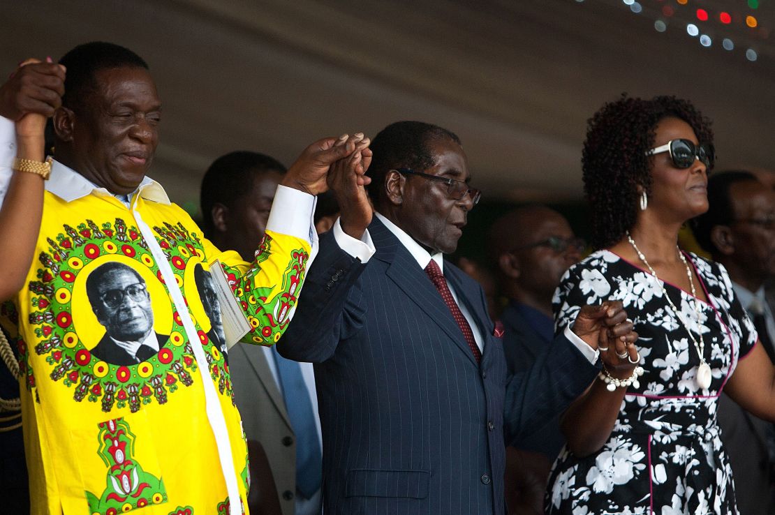 Mugabe holds hands with former Vice President Emmerson Mnangagwa (L) and Grace (R) during his birthday celebrations last year. 