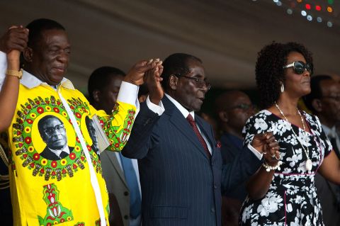Zimbabwean President Robert Mugabe holds hands with Vice President Emmerson Mnangagwa and his wife during his birthday celebrations on February 27, 2016.