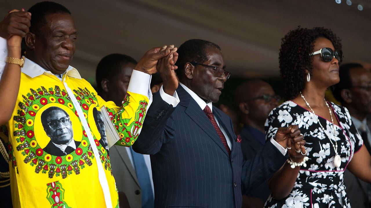 Mugabe holds hands with former Vice President Emmerson Mnangagwa (L) and Grace (R) during his birthday celebrations last year.