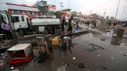 Men clean up the site of a bombing at a market in the Sadr City area of Baghdad Sunday. ISIS claimed responsibility for the attack.