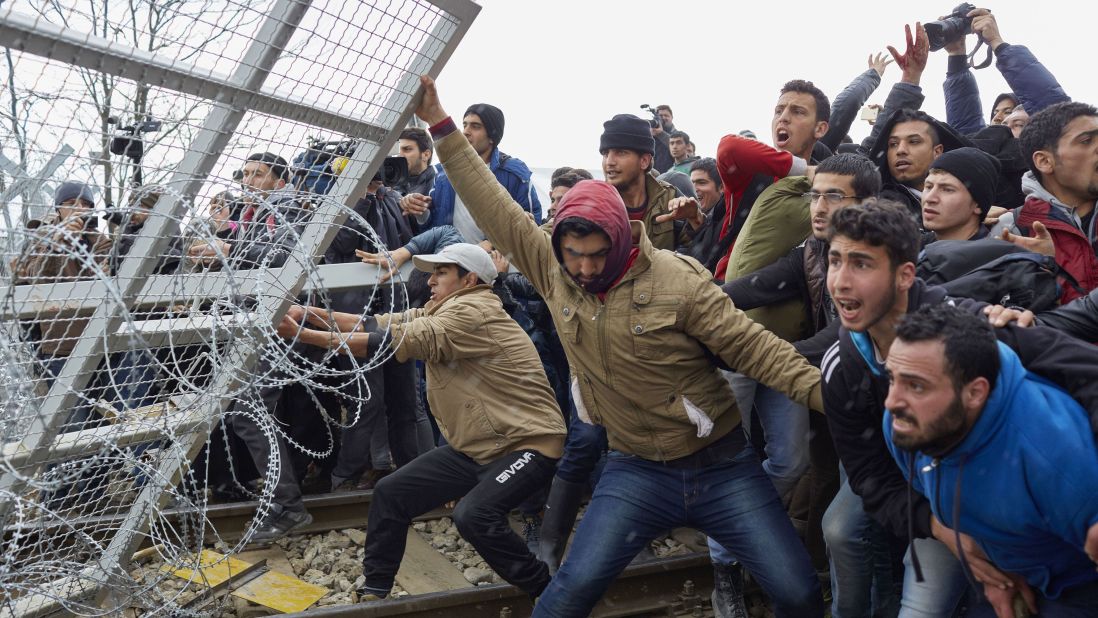 Refugees break through a barbed-wire fence on the Greece-Macedonia border in February 2016, as tensions boiled over regarding new travel restrictions into Europe.