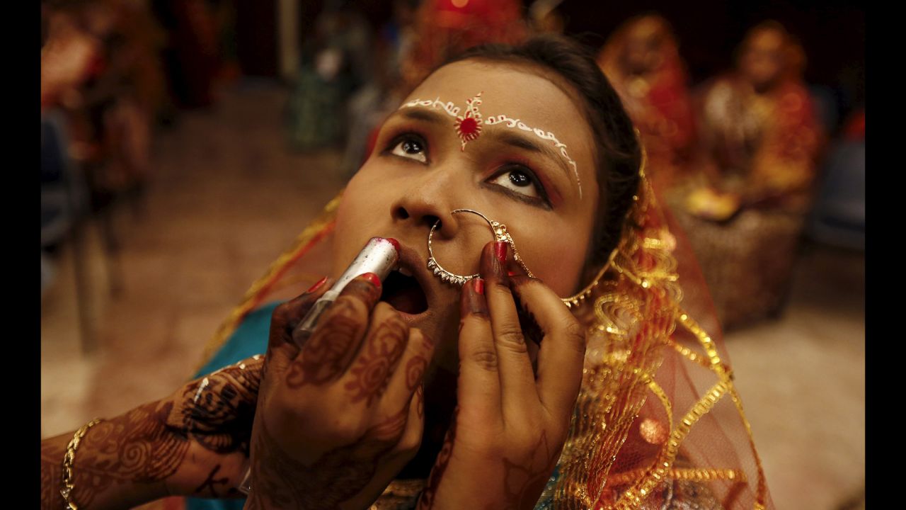 A bride has makeup applied before the start of a daylong mass marriage ceremony featuring 150 Hindu, Muslim and Christian couples from villages across the state.