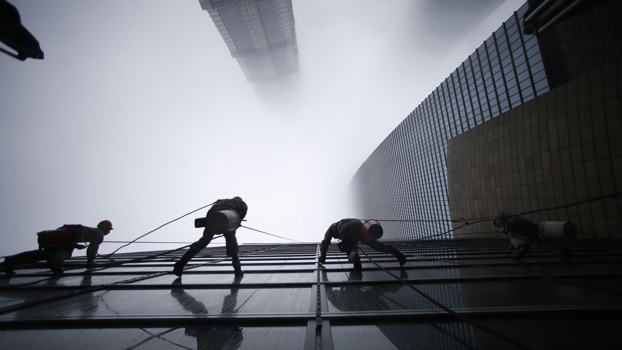 Workers clean the Shanghai World Financial Center in the financial district of Pudong. Shanghai Tower is seen at the top of the picture, and Jin Mao Tower is to the left. 