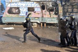 A police officer throws a tear gas canister during the dismantling of half of the "Jungle" migrant camp.