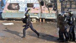 A police officer throws a tear gas canister during the dismantling of half of the "Jungle" migrant camp.