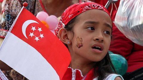 A girl holding the Singapore flag sings along during an event to celebrate Singapore's 44th National Day on August 9, 2009. In his National Day message Singapore Prime Minister Lee Hsien Loong indicated that Singapore's economic contraction in the first half of the year was not as bad as feared and that the country is now in a stronger position than at the start of the year.