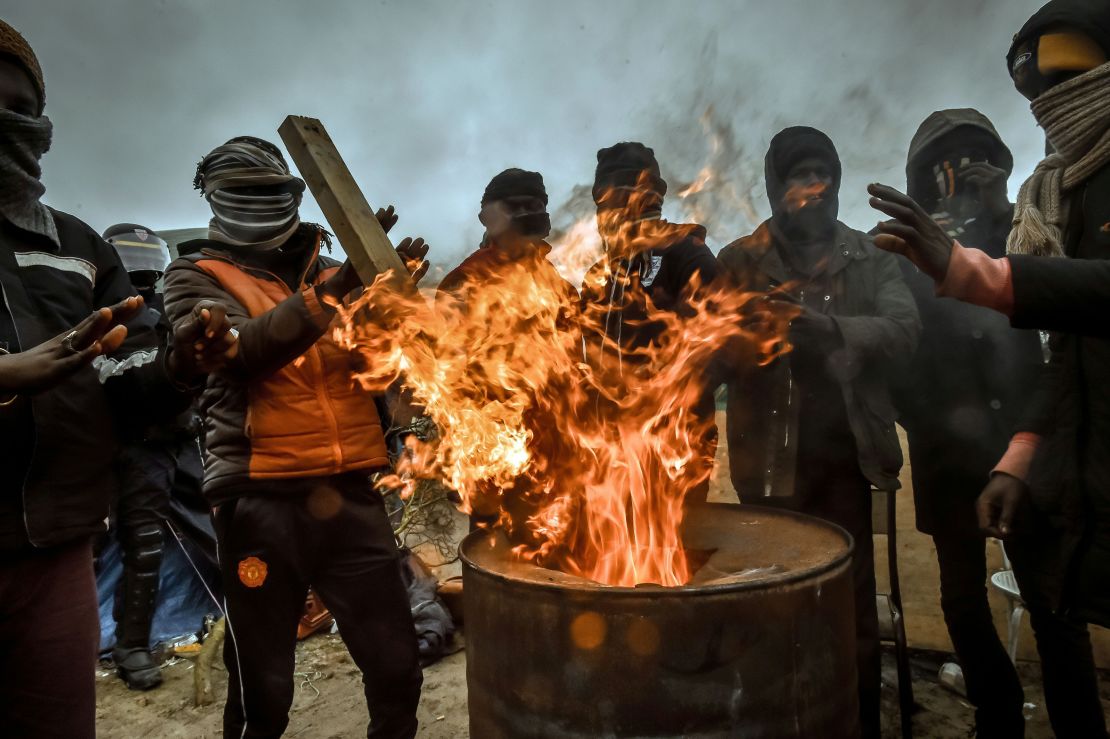 Migrants keep warm as French authorities dismantle structures at the "Jungle" migrant camp in Calais Tuesday.