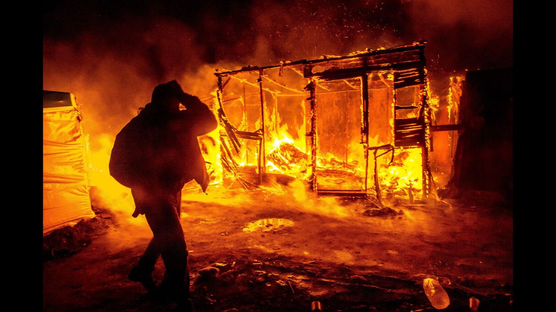 A migrant walks past a burning shack in the southern part of the "Jungle" migrant camp in Calais, France, in March 2016. Part of the camp was being demolished -- and the inhabitants relocated -- in response to unsanitary conditions at the site.