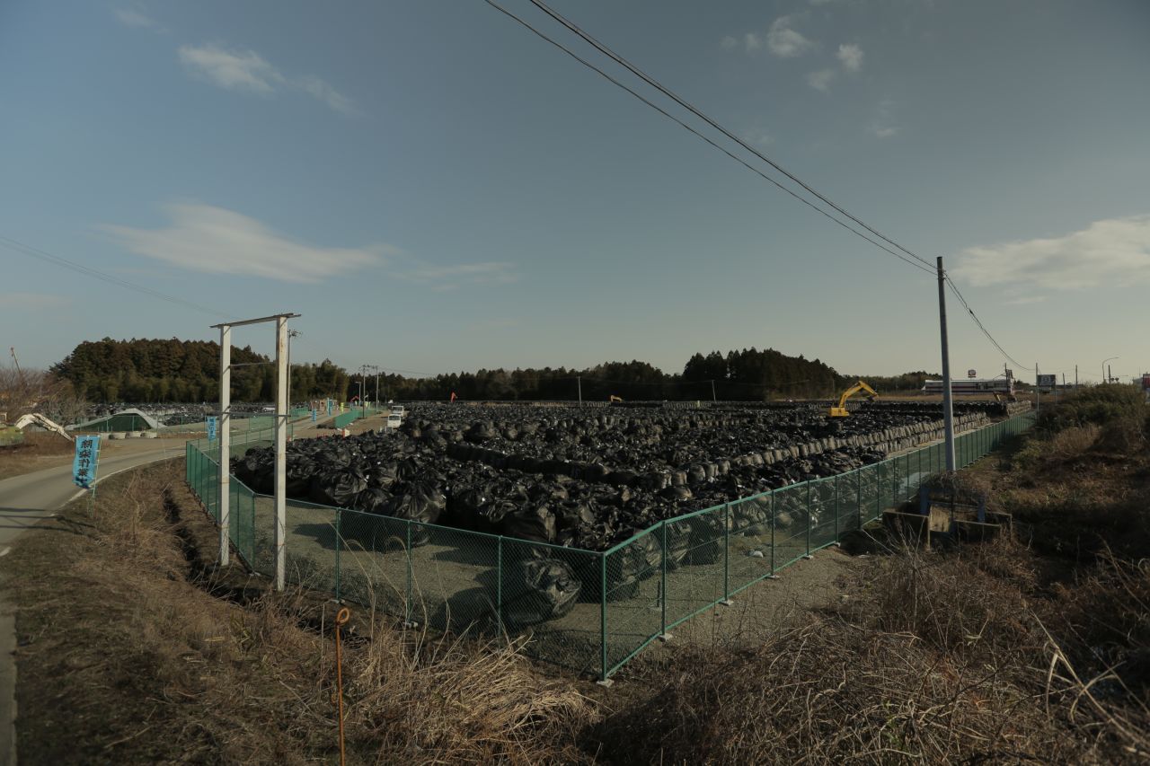 A mountain of black bags filled with contaminated soil sits piled on a roadside in Tomioka, Fukushima. A massive national project to remove topsoil and vegetation contaminated by the Fukushima nuclear disaster will produce at least 22 million square meters of radioactive waste. 